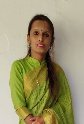Portrait of Dr. Kapoor wearing traditional attire with academic books in background